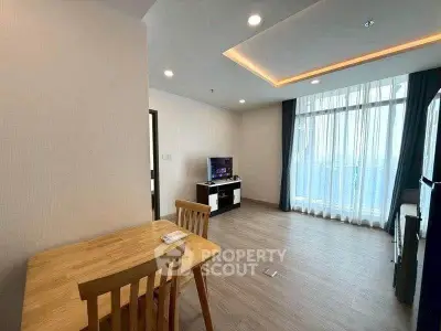 Modern living room with wooden flooring and stylish furniture, featuring a TV and large windows for natural light.