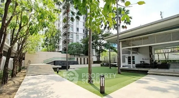 Modern apartment complex with lush green garden and sleek architecture.
