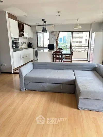 Spacious open-plan living room with modern kitchen and city view balcony.