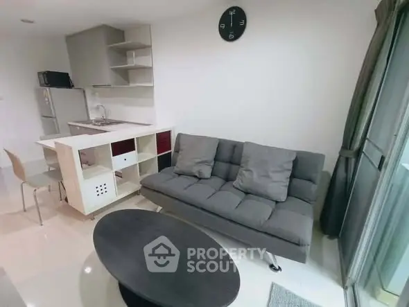 Modern living room with sleek kitchen and cozy sofa in open layout apartment.
