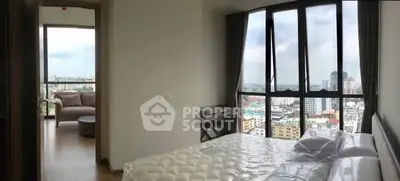Spacious bedroom with panoramic city view and adjacent living area in modern apartment.