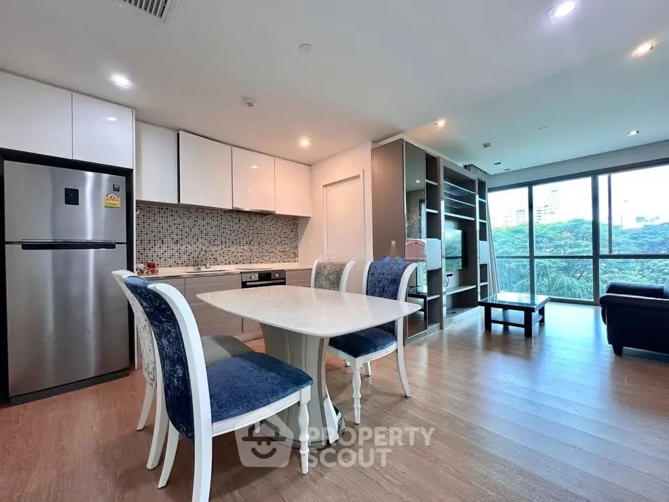 Modern open-layout kitchen and living room with elegant dining set and scenic window view.