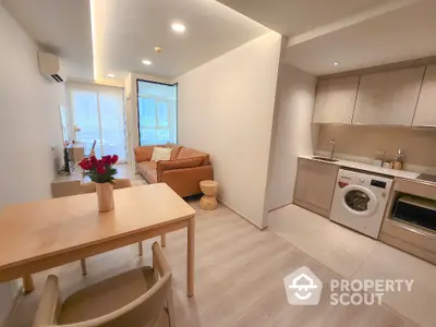 Modern open-plan living room with kitchen featuring washing machine and cozy seating area.