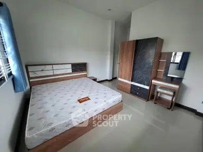 Spacious bedroom with modern wooden furniture and large windows for natural light.