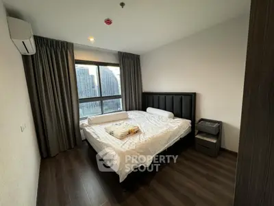 Modern bedroom with large window and city view, featuring a comfortable bed and sleek design.