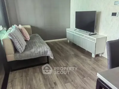 Modern living room with stylish sofa and flat-screen TV on sleek cabinet.