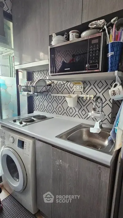 Compact kitchen with modern appliances and stylish backsplash in a cozy apartment.