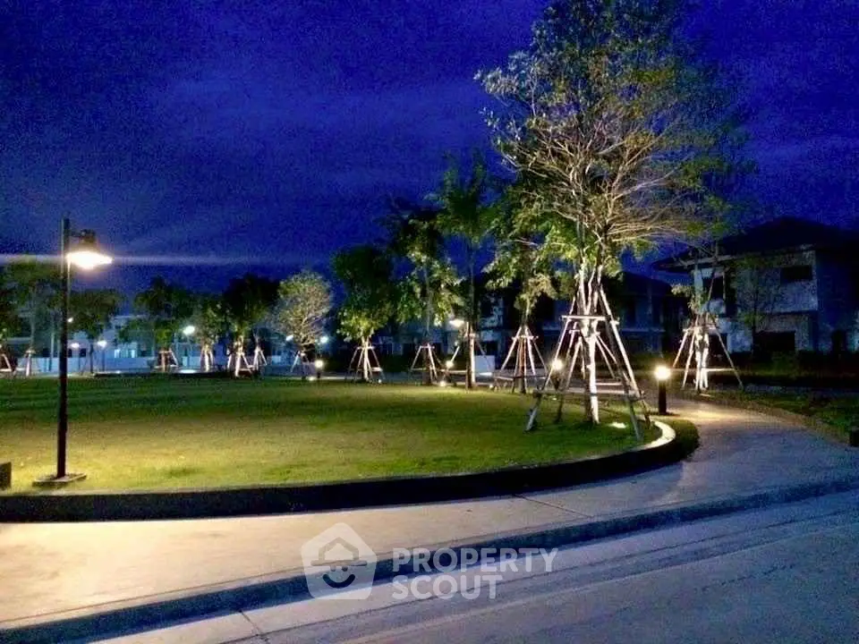 Beautifully lit garden area in a residential complex at night, showcasing serene landscaping.