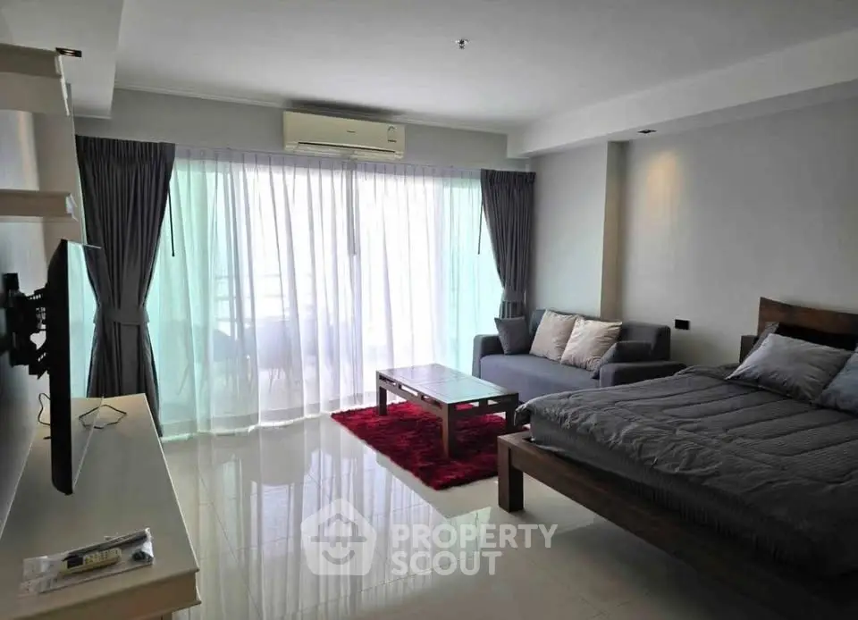 Modern studio apartment with cozy living area and large windows for natural light.