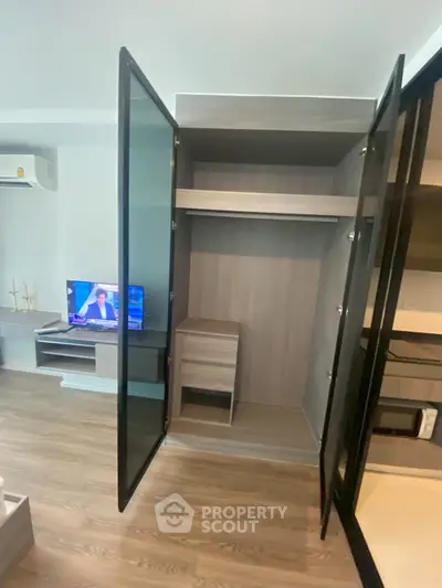 Modern apartment interior with open wardrobe and TV in living area