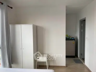 Modern minimalist bedroom with white wardrobe and washing machine corner.