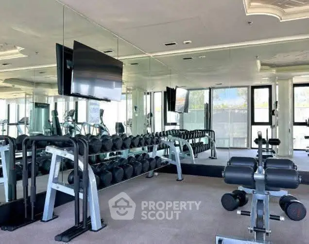 Luxurious gym with modern equipment and mirrored walls in upscale residential building.