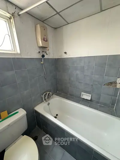 Cozy bathroom with bathtub and tiled walls, perfect for relaxation and comfort.