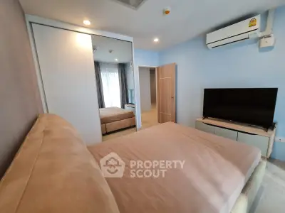 Modern bedroom with sleek design, featuring a large bed, mirrored closet, and wall-mounted TV.