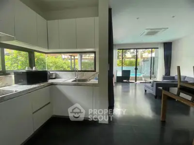 Modern open-layout kitchen and living room with pool view, sleek design and natural light.
