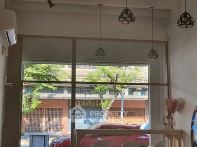 Chic urban cafe interior with large windows and modern pendant lights.