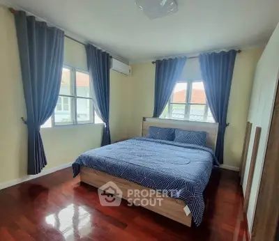 Spacious bedroom with elegant decor and large windows offering natural light.