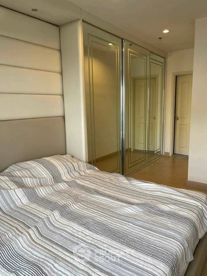 Spacious bedroom with mirrored wardrobe and cozy bed in modern apartment.