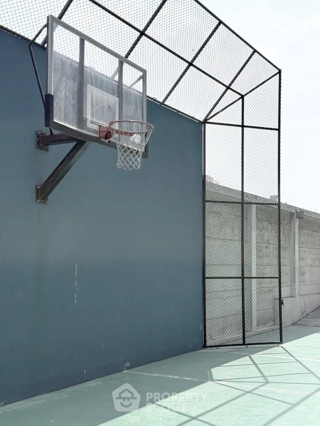 Modern outdoor basketball court with sleek design and high fence, perfect for sports enthusiasts.