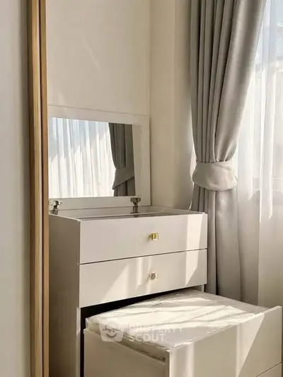 Elegant bedroom corner with vanity and soft natural light through curtains.