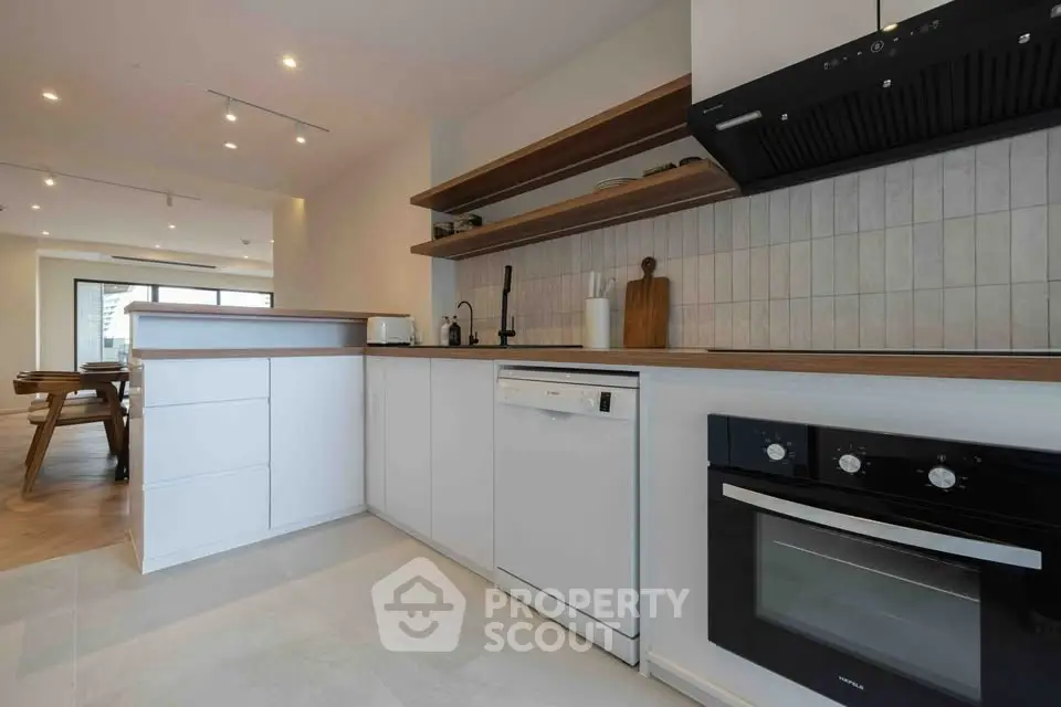 Modern kitchen with sleek white cabinetry and built-in appliances in open layout.