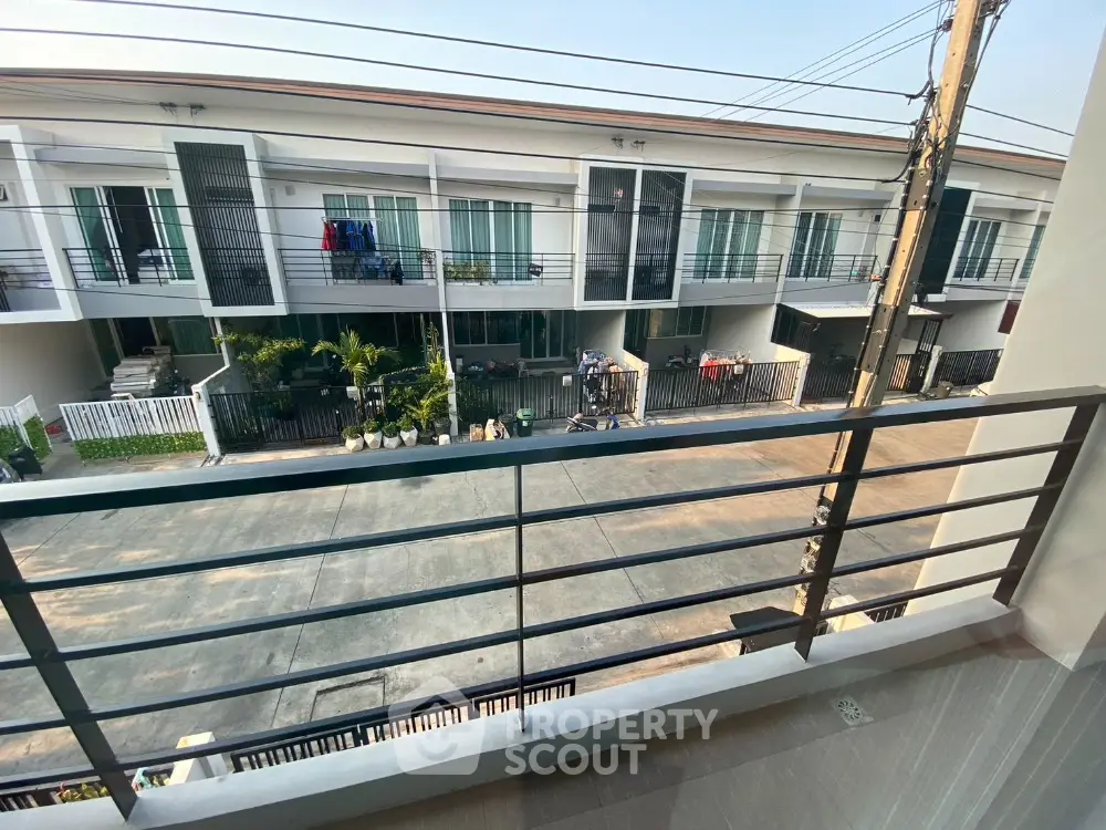 Spacious balcony with a serene view of a modern townhouse complex, showcasing a peaceful suburban lifestyle with ample outdoor space.