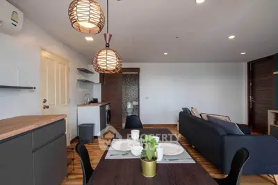 Modern open-plan living room with stylish dining area and cozy seating, featuring contemporary lighting and wooden flooring.