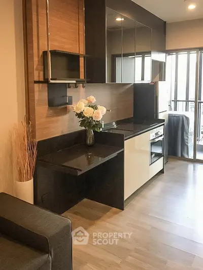 Modern kitchen with sleek cabinetry and open layout, featuring a stylish black countertop and elegant decor.