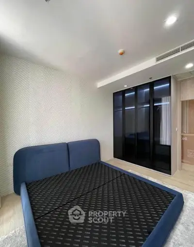 Modern bedroom with stylish blue bed and sleek black wardrobe in a contemporary apartment.