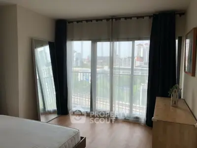 Spacious bedroom with large windows and city view, featuring modern decor and wooden flooring.