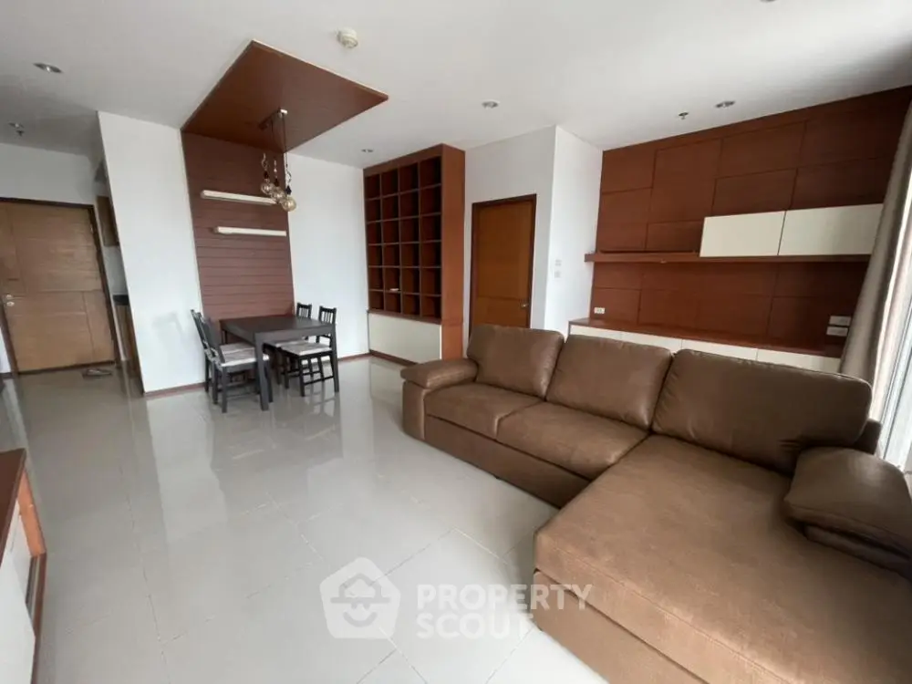 Spacious living room with modern brown sofa and dining area in open layout apartment.