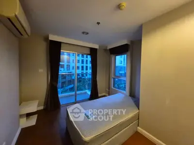 Cozy bedroom with large windows and balcony access in modern apartment