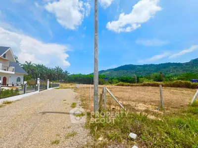 Scenic land plot with mountain views and adjacent house, ideal for development.