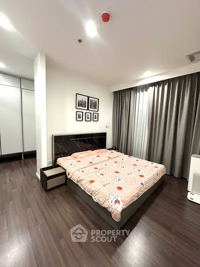 Spacious modern bedroom with stylish decor and ample natural light, featuring sleek wooden flooring and elegant curtains.