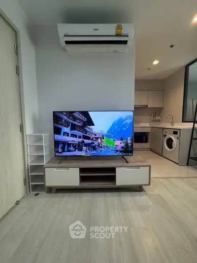 Modern living room with TV, air conditioning, and kitchen appliances in a stylish apartment.