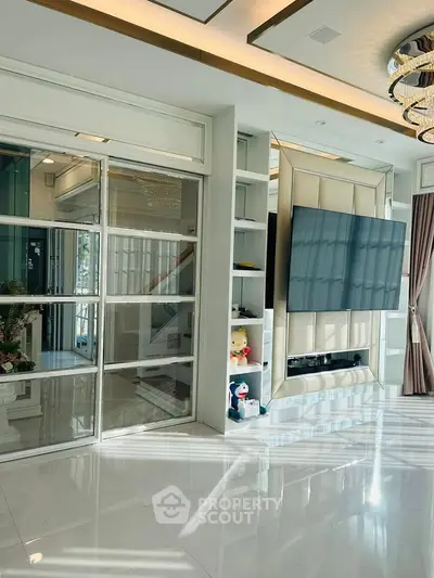 Luxurious living room with modern decor, large TV, and elegant lighting, perfect for entertainment and relaxation.