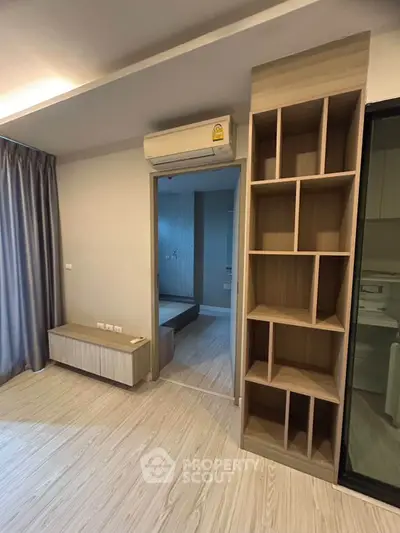 Modern apartment interior with sleek wooden flooring and built-in shelving, featuring an air conditioning unit.