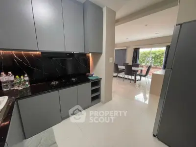 Modern kitchen with sleek cabinets and open layout leading to dining area