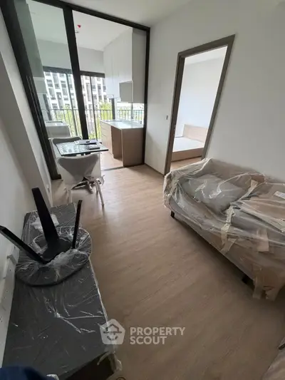 Modern apartment interior with balcony, featuring sleek furniture and wooden flooring.