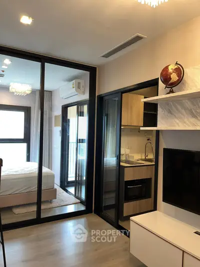 Modern apartment interior with glass partition, cozy bedroom, and sleek kitchen area.