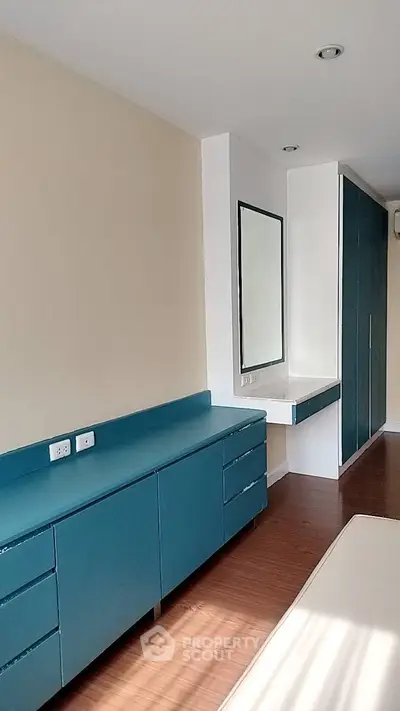 Spacious bedroom with modern blue cabinetry and sleek hardwood flooring