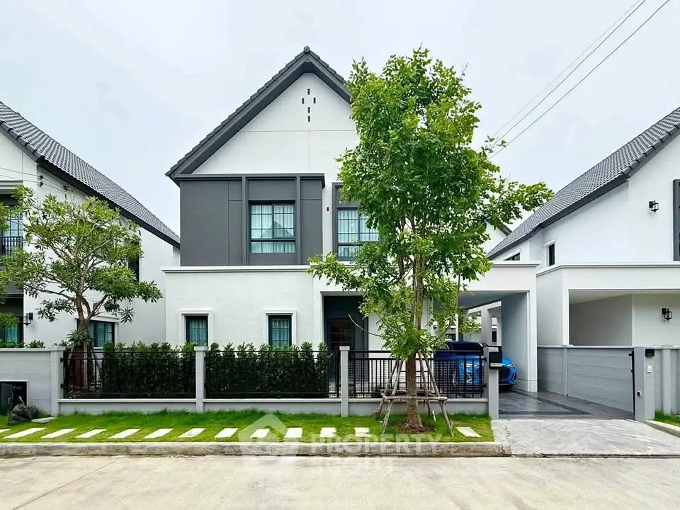 Modern two-story house with sleek design and manicured lawn in a suburban neighborhood.