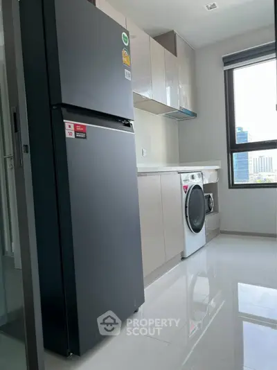 Modern kitchen with sleek appliances and ample natural light in a high-rise apartment.