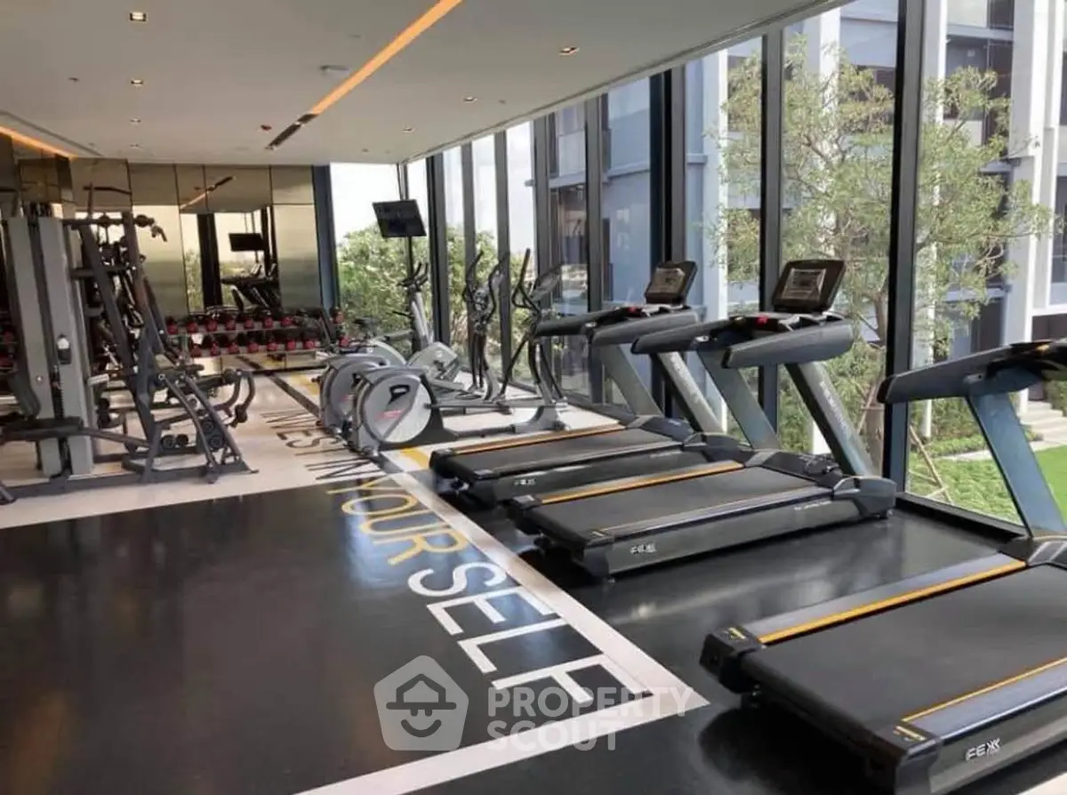 Modern gym with large windows and state-of-the-art fitness equipment in luxury residential building.