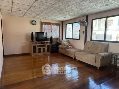 Spacious living room with wooden floors and cozy seating, perfect for relaxation and entertainment.