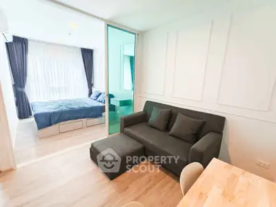 Modern studio apartment with cozy living area and bedroom separated by glass partition.