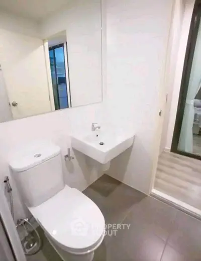 Modern bathroom with sleek fixtures and minimalist design, featuring a wall-mounted sink and toilet.