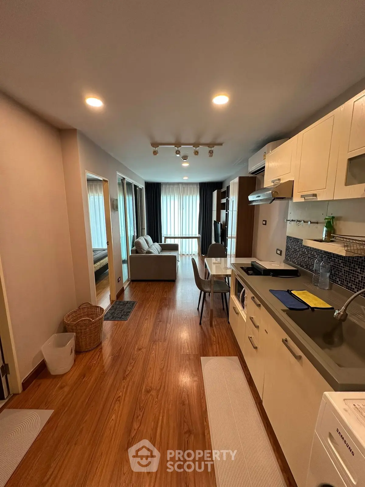 Modern open-plan kitchen and living area with wooden flooring and natural light.