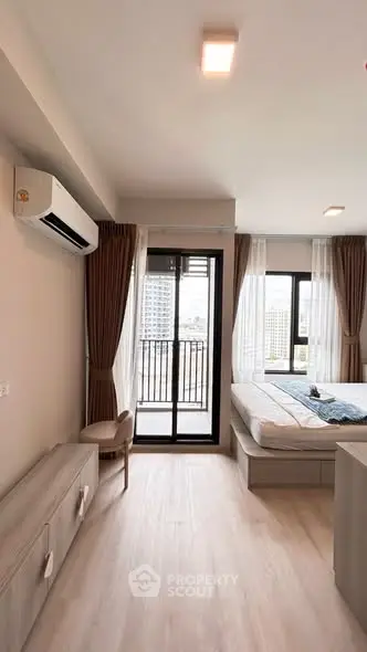 Modern bedroom with balcony access and city view, featuring sleek furniture and natural light.