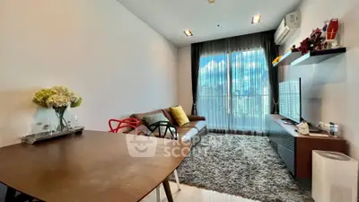 Modern living room with stylish decor, large window, and cozy seating area.